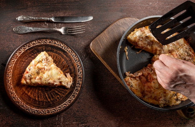 Pizza caseira com tomate, mussarela e presunto em uma mesa de madeira