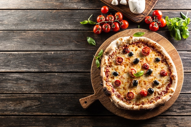 Pizza caseira com tomate, queijo mozzarella, azeitonas e manjericão - vista de cima do pof