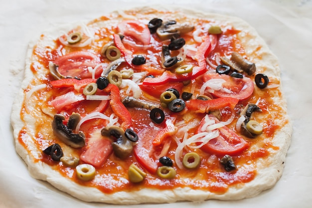 Pizza caseira crua com tomates, azeitonas, pimentão