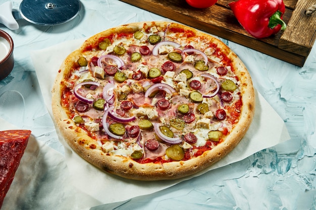 Pizza caseira de carne assada com cebola, queijo, presunto, pepinos em conserva com molho vermelho. Composição com pizza crocante, tomate.