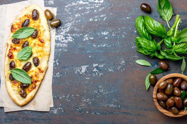 Pizza caseira oval com azeitonas inteiras e queijo