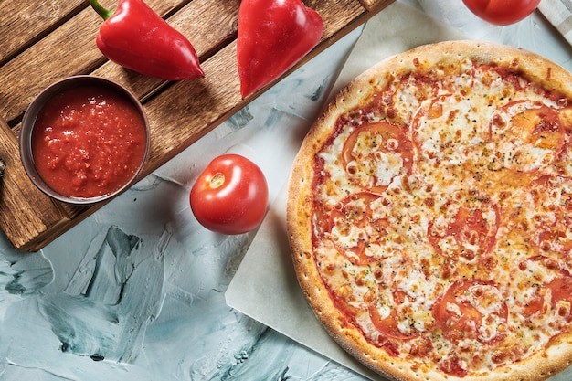 Pizza casera al horno margherita o margarita con tomate, queso mozzarella, salsa roja. Composición con pizza crujiente, tomates.