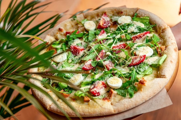 Pizza casera con ensalada César una interesante porción de ensalada con carne de pollo