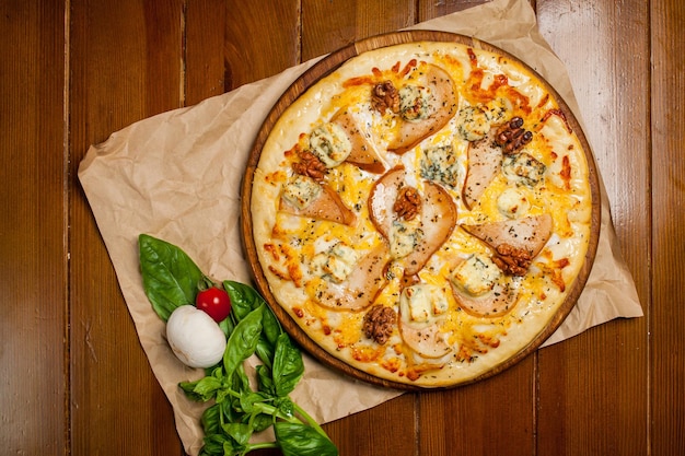 Pizza casera con nueces de pera y gorgonzola en un papel artesanal de mesa de madera marrón