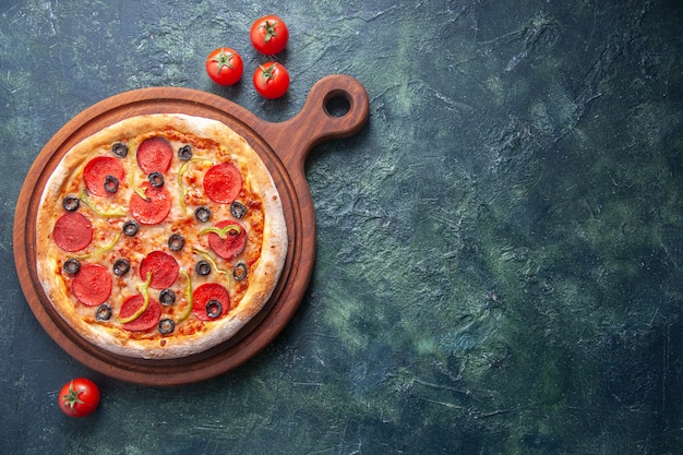 Pizza casera en tabla de cortar de madera y tomates en superficie oscura aislada