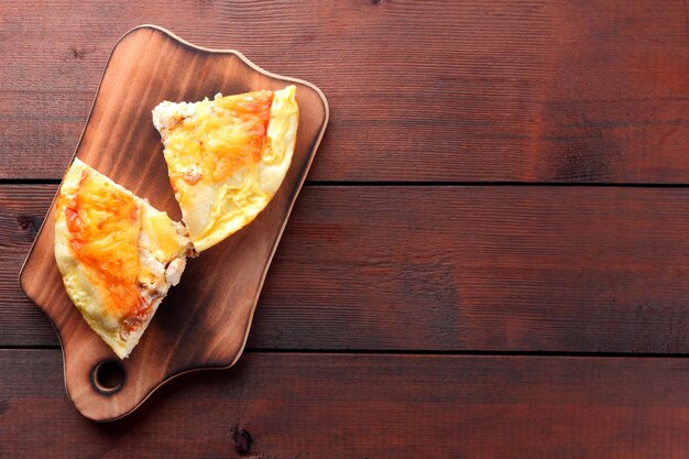 Pizza casera en tabla de cortar Pizza en rodajas sobre fondo de madera en estilo rústico Copiar espacio