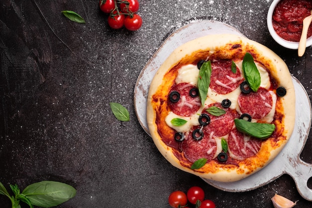 Pizza casera con tomate y albahaca en una pizarra blanca