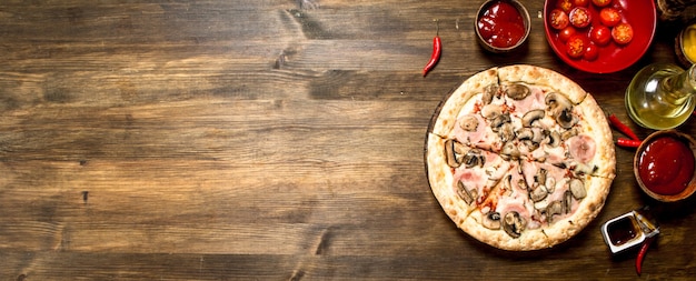 Pizza con champiñones y jamón. Sobre una mesa de madera.