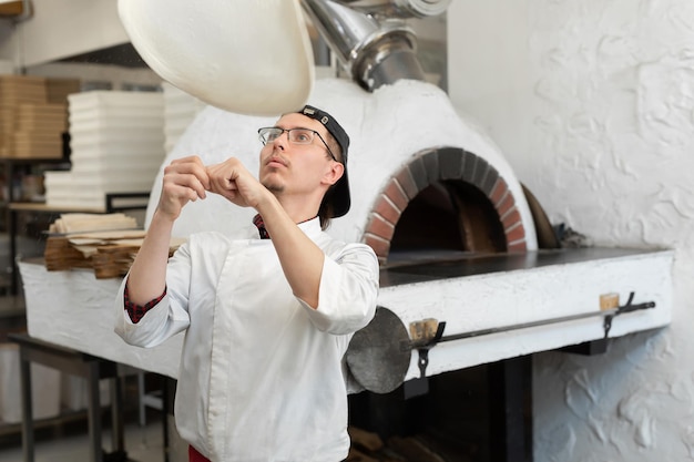 Pizza Chef dreht den Pizzateig in der Luft, um ihn dünn und weich zu machen