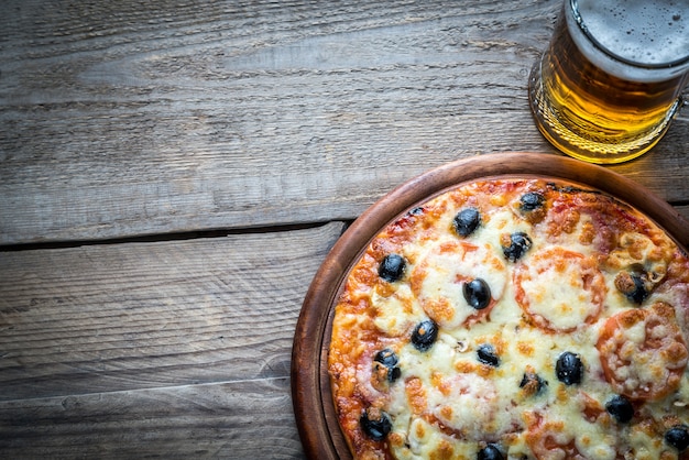 Pizza cocinada con un vaso de cerveza.