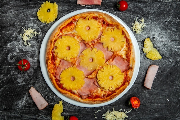 Pizza com abacaxi e mussarela em fundo de madeira preta