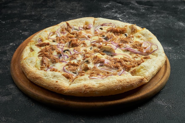 Foto pizza com atum, cebola e cogumelos em um fundo preto de pedra. vista de ângulo de 45 graus. close-up, foco seletivo