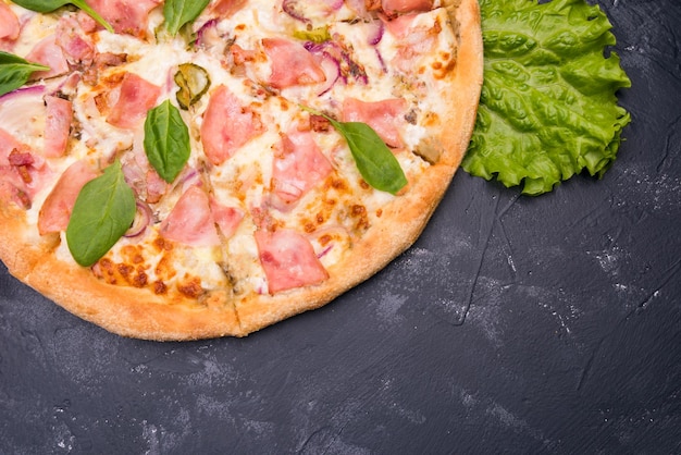 Pizza com bacon e verduras em um fundo escuro
