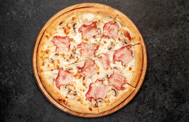 Pizza com cogumelos bacon e queijo em um fundo de pedra