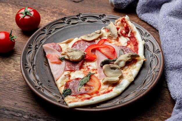 Pizza com cogumelos de presunto e bacon em um prato de barro em um fundo de madeira marrom