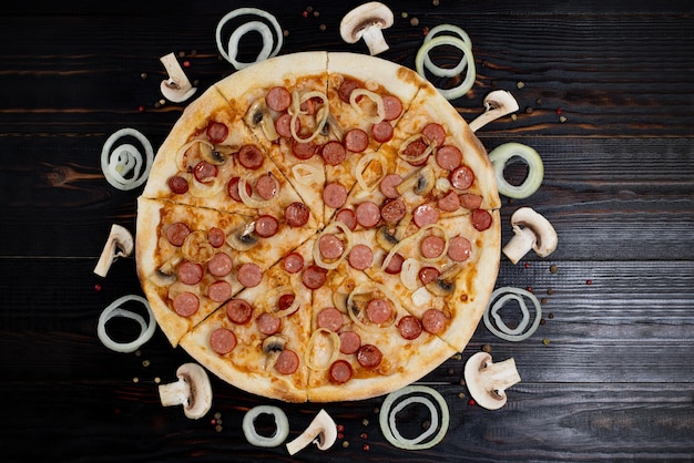 Foto pizza com cogumelos e cebolas caramelizadas em fundo de madeira vista superior