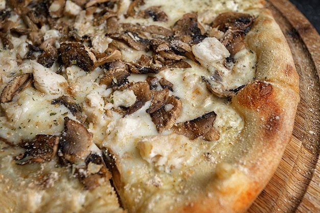 Pizza com cogumelos e frango em uma placa de madeira