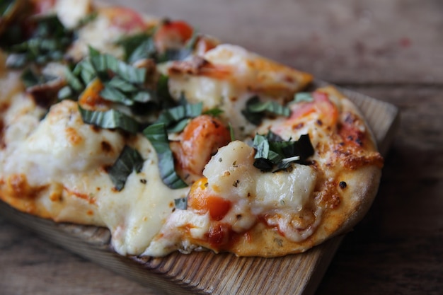 Pizza com frutos do mar e tomates em uma mesa de madeira, comida italiana