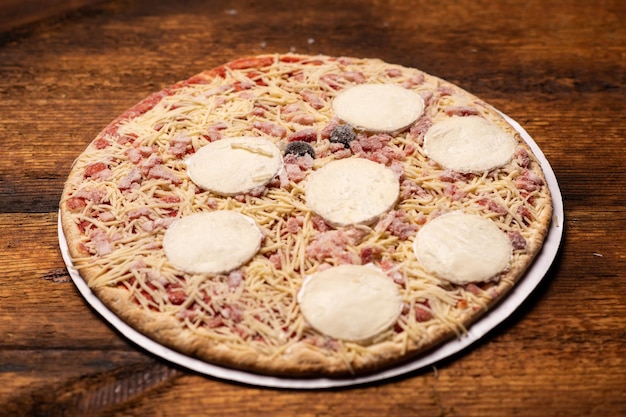 Pizza com grandes círculos de queijo em um fundo de madeira