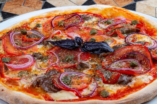 Pizza com lombo de vitela e anéis de cebola doce na mesa de pedra