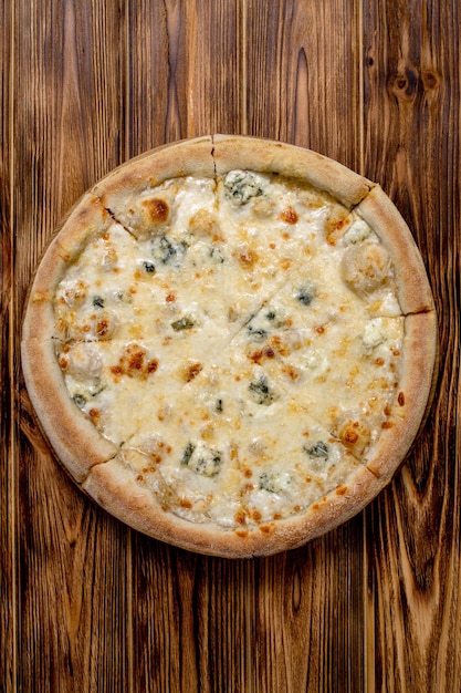 Foto pizza com quatro queijos mussarela queijo azul queijo parmesão cozinha italiana em um fundo de madeira vista de cima