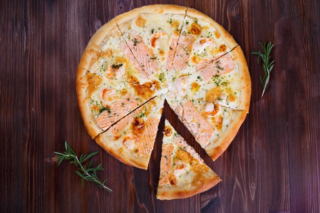 Pizza com queijo carne pimentas e tomates na madeira