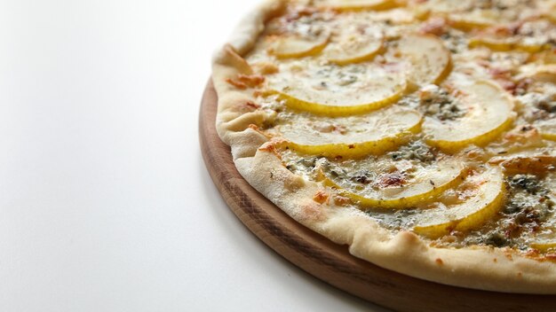 Pizza com queijo e frutas de pêra na tábua de madeira