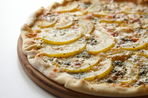 Pizza com queijo e frutas de pêra na tábua de madeira