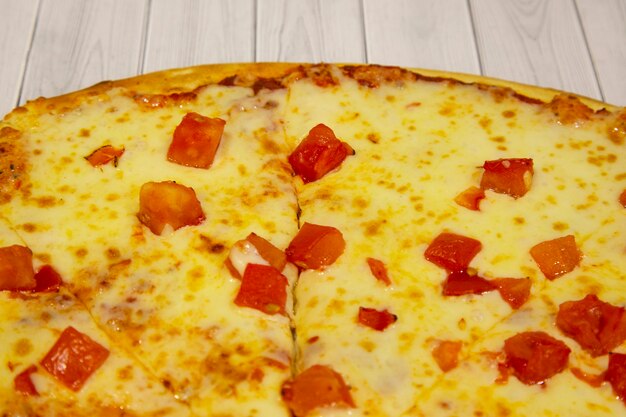 Pizza com queijo e tomate, culinária italiana, sobre fundo claro de madeira