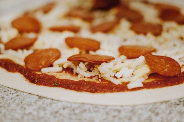 Pizza com queijo parmesano, peperoni e tomate sem cocinar