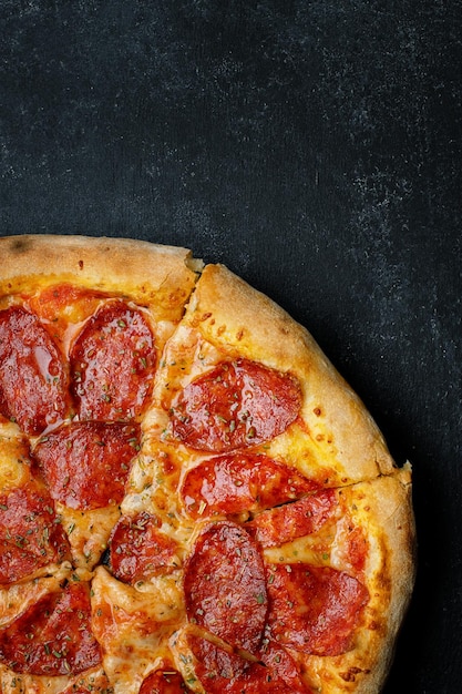 Pizza com queijo salsicha e especiarias em concreto escuro