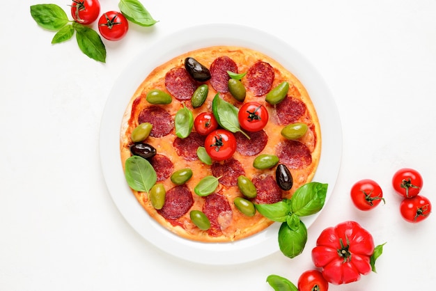 Pizza com salame e azeitonas decorada com folhas frescas de manjericão vista de cima