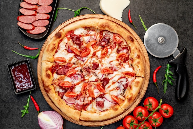 pizza com salsichas cogumelos tomate e queijo sobre um fundo de pedra