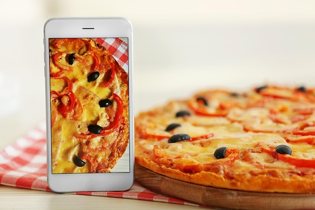 Pizza com smartphone na mesa Conceito de blog de comida