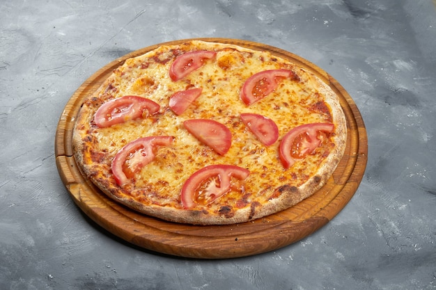 Pizza com tomate e queijo em um fundo cinza