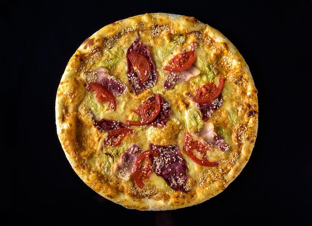 Pizza com tomate, fiambre e queijo numa mesa de madeira