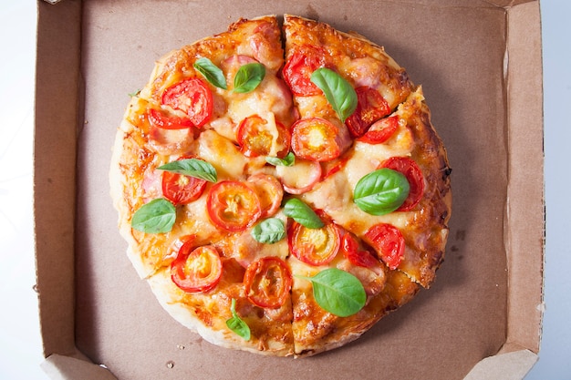 Pizza com tomate, linguiça e queijo em caixa de papelão
