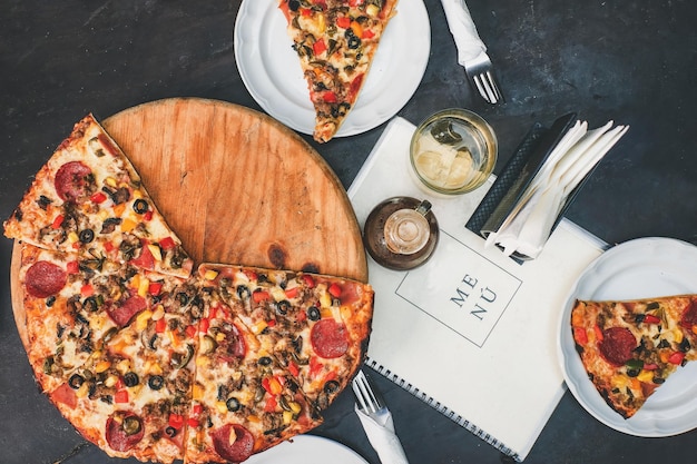 Pizza combinada en una mesa de restaurante con platos y utensilios