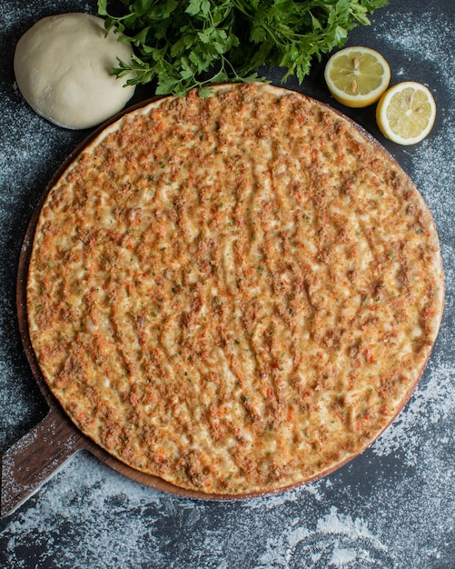 Una pizza con una corteza y algunos limones al lado.