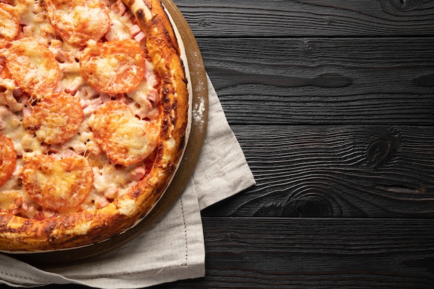 Pizza cozida em um fundo de madeira, lugar para texto, vista de cima