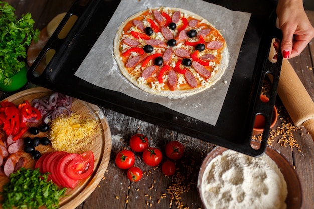 Pizza crua com ingredientes na assadeira