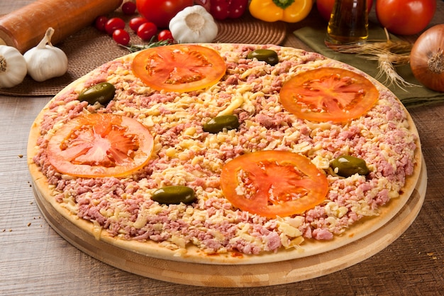 Pizza crua com queijo e presunto na mesa de madeira