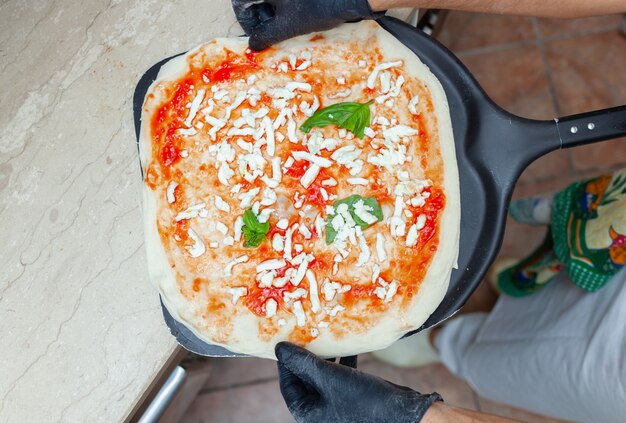 Pizza crua do margherita na pá do cozimento.