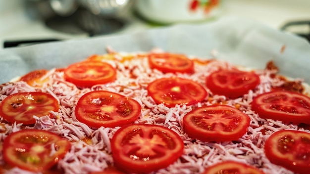 Pizza cruda con carne, queso y tomates