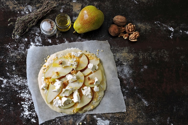 Pizza cruda casera con pera, queso y nueces.