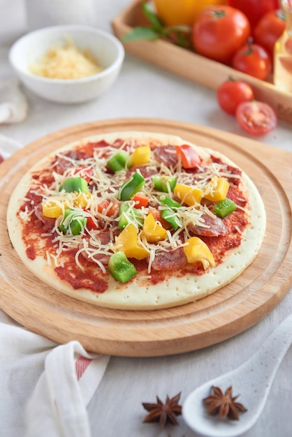 Pizza cruda con ingredientes en el fondo