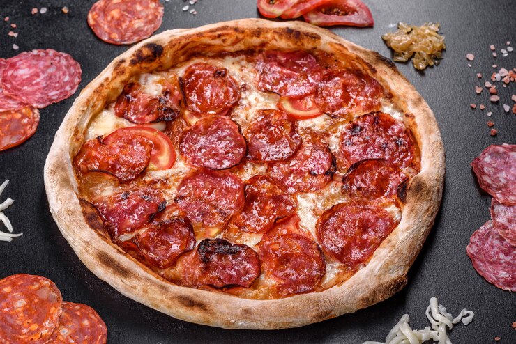 Foto pizza de calabresa com molho de pizza, queijo mussarela e calabresa. pizza na mesa com ingredientes