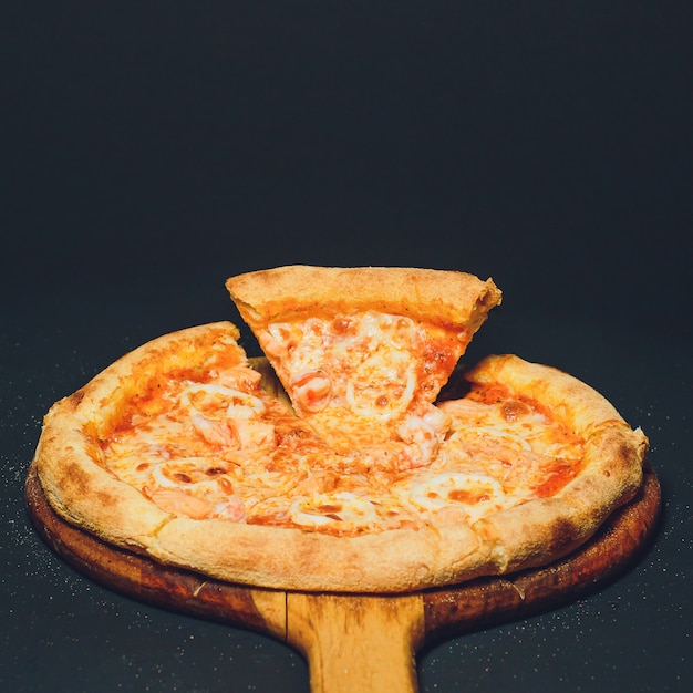 Pizza de calabresa, orégano em uma mesa preta
