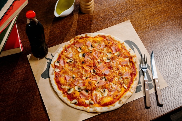 Pizza de cogumelos com adição de queijo mussarela e ervas em uma mesa de madeira, vista de cima