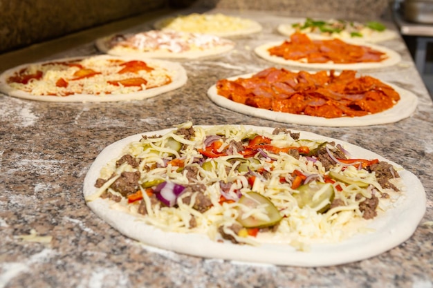 Pizza de linha com queijo preparado para assar Pizza de processo de fabricação de pizza de linha em uma mesa com massa